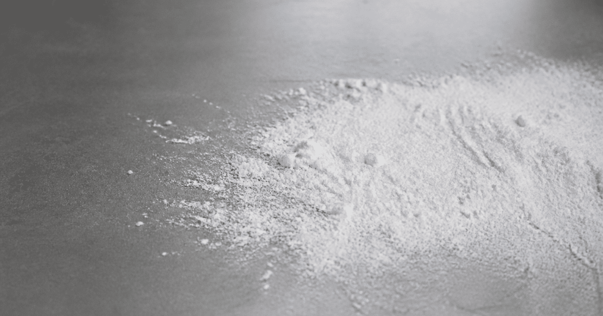 Poudre blanche versée sur surface grise lisse