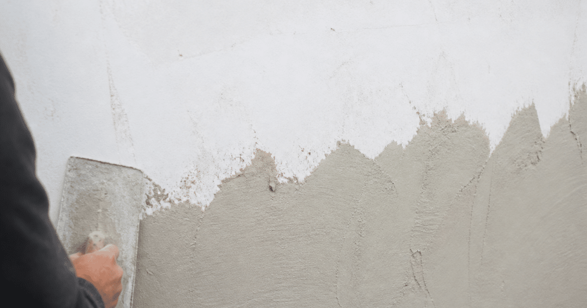 Couches d'enduit appliquées progressivement sur surface murale blanche