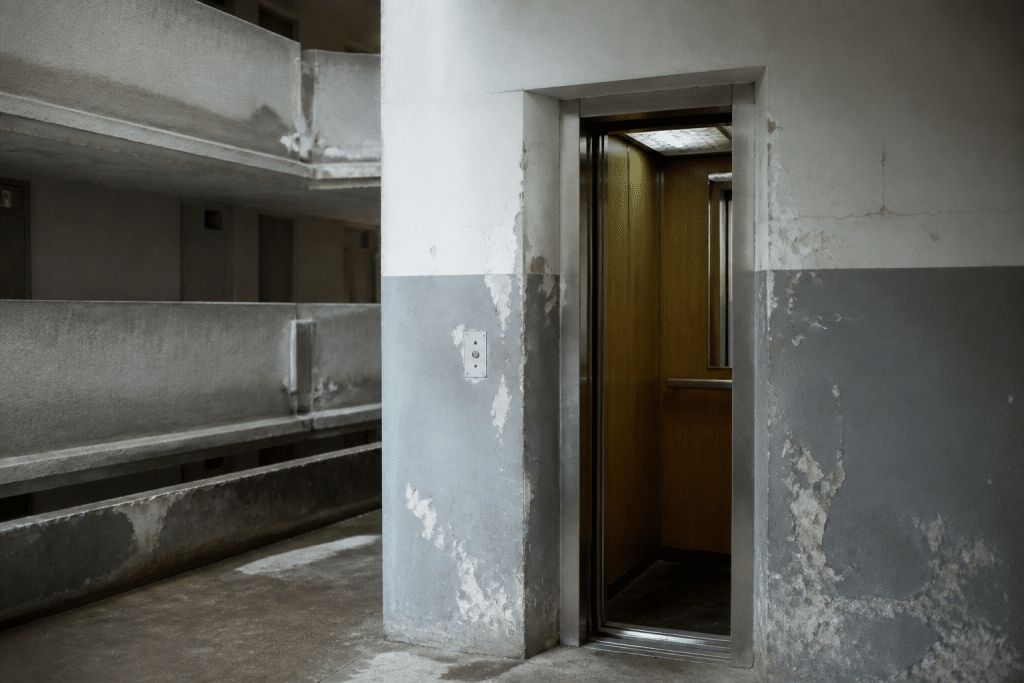 Immeuble gris avec ascenseur défaillant et facade usee