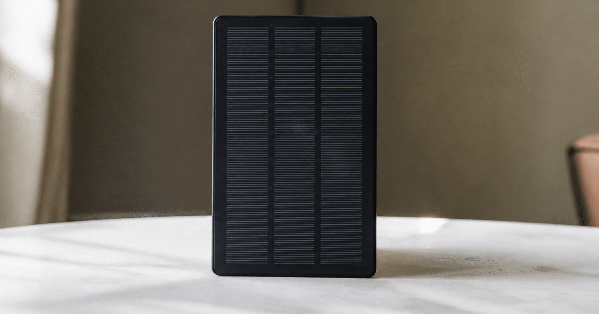Petit panneau solaire noir posé verticalement sur surface blanche