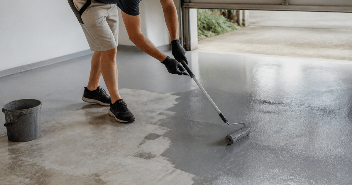 Personne appliquant peinture grise sur sol beton garage