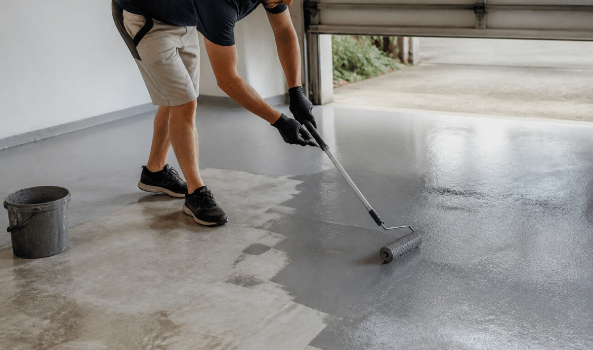 Personne appliquant peinture grise sur sol beton garage