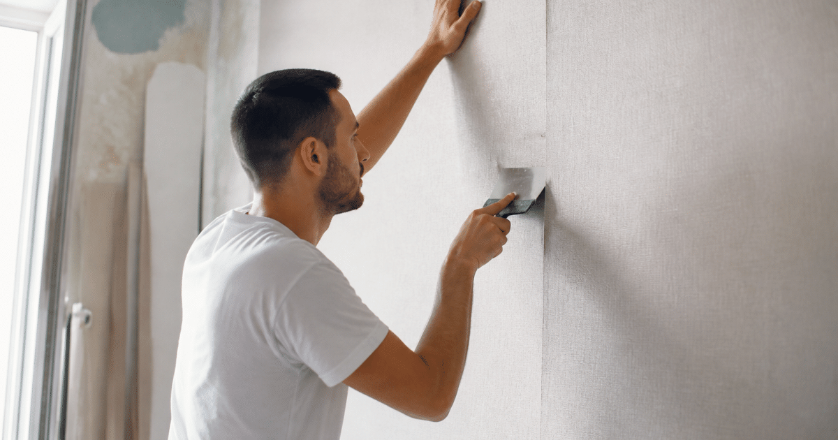 Ouvrier collant papier peint sur mur avec spatule