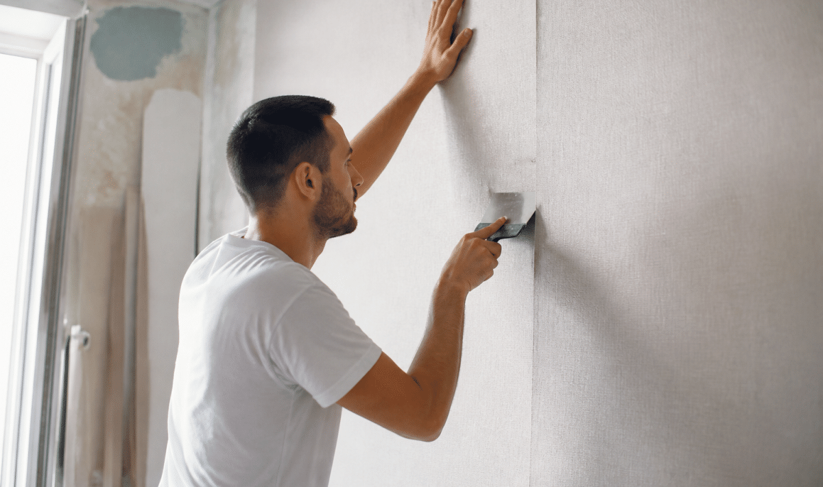 Ouvrier collant papier peint sur mur avec spatule