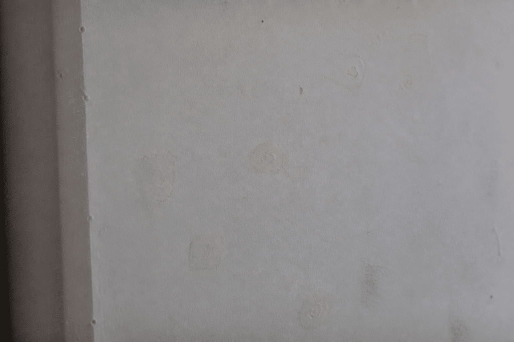 Mur blanc avec trous rebouchés et poussiere visible