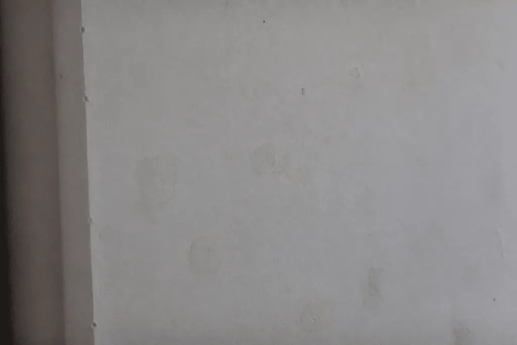 Mur blanc avec trous rebouchés et poussiere visible