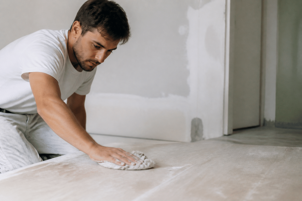 Ouvrier nettoie surface poussiereuse avant application peinture