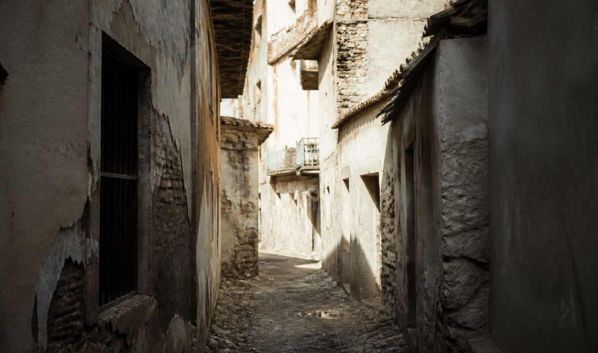 Rue urbaine avec immeubles délabres et passages sombres entre batiments