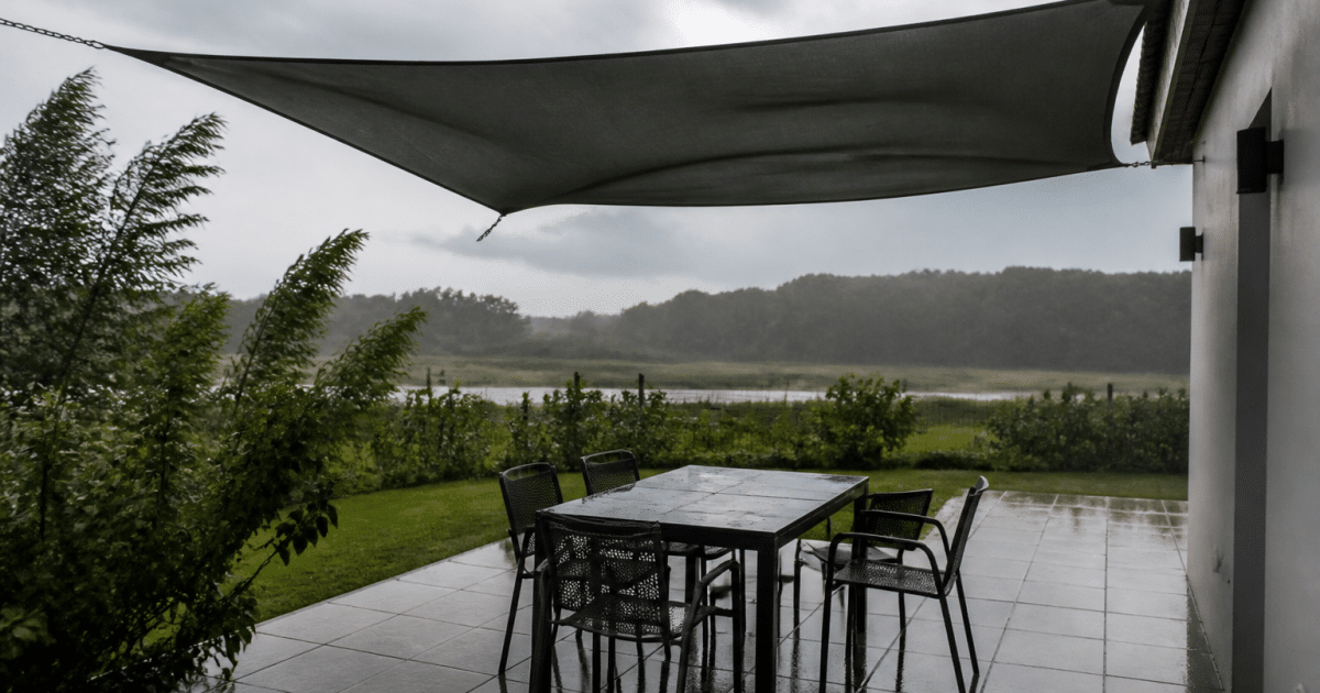 Voile d'ombrage tendue horizontalement au-dessus terrasse battue par vent