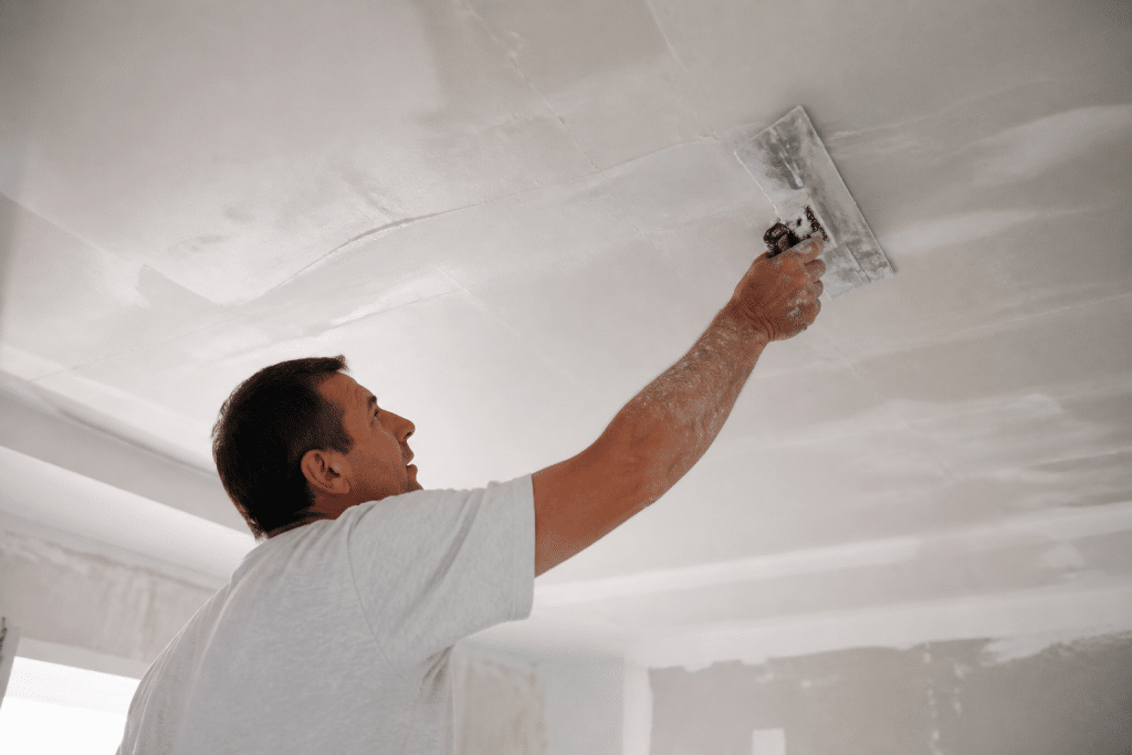 Applicateur etale enduit blanc sur plafond avec spatule