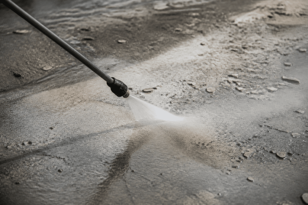 Nettoyeur haute pression projette eau sur surface béton dégradée