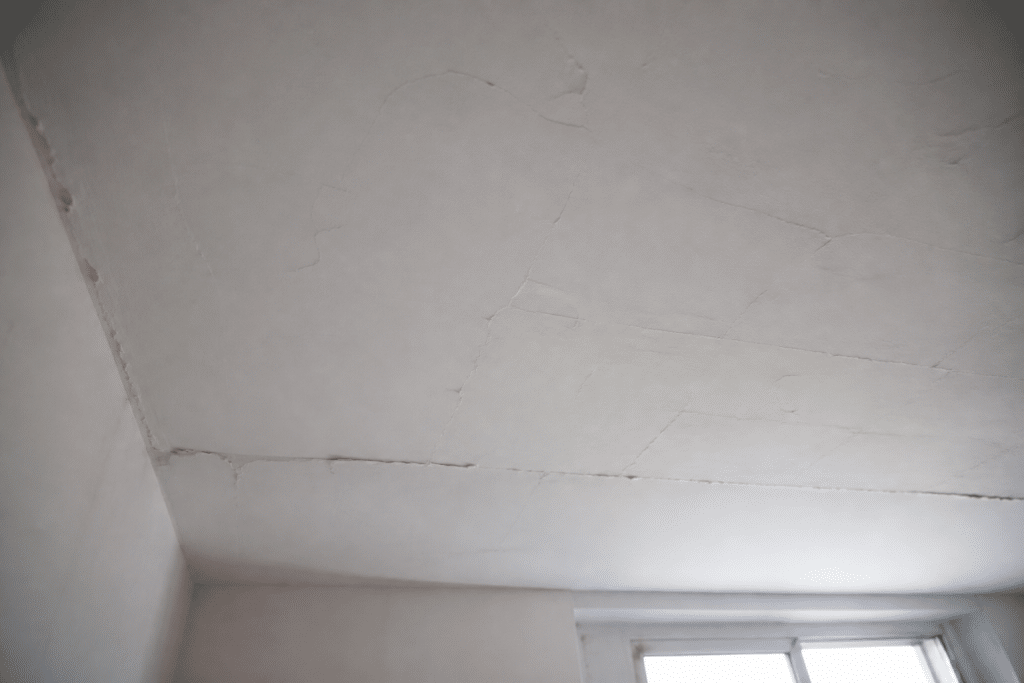 Plafond avec enduit mal applique montrant fissures et defauts
