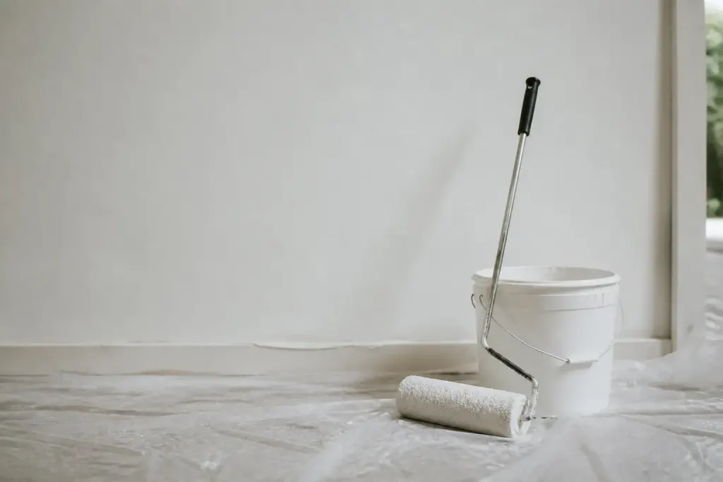Mur blanc lisse avec rouleau et pot de peinture