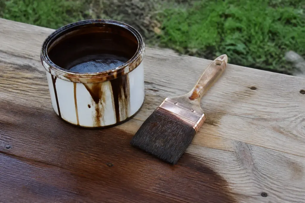 Pot de lasure et pinceau sur planche de bois